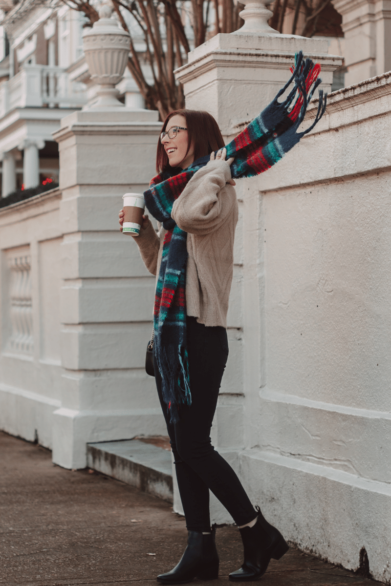 girl flips plaid wool scarf and holds coffee cup