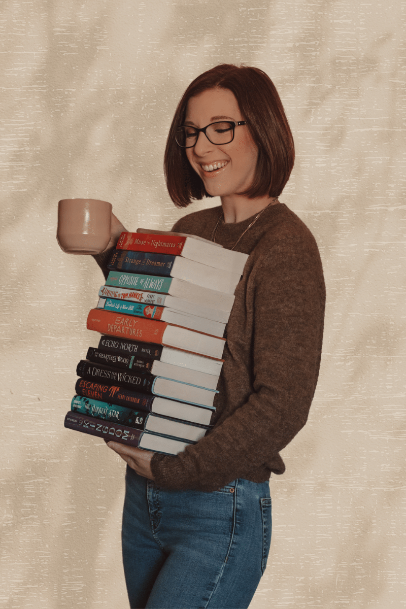 woman holding a stack of books and coffee mug