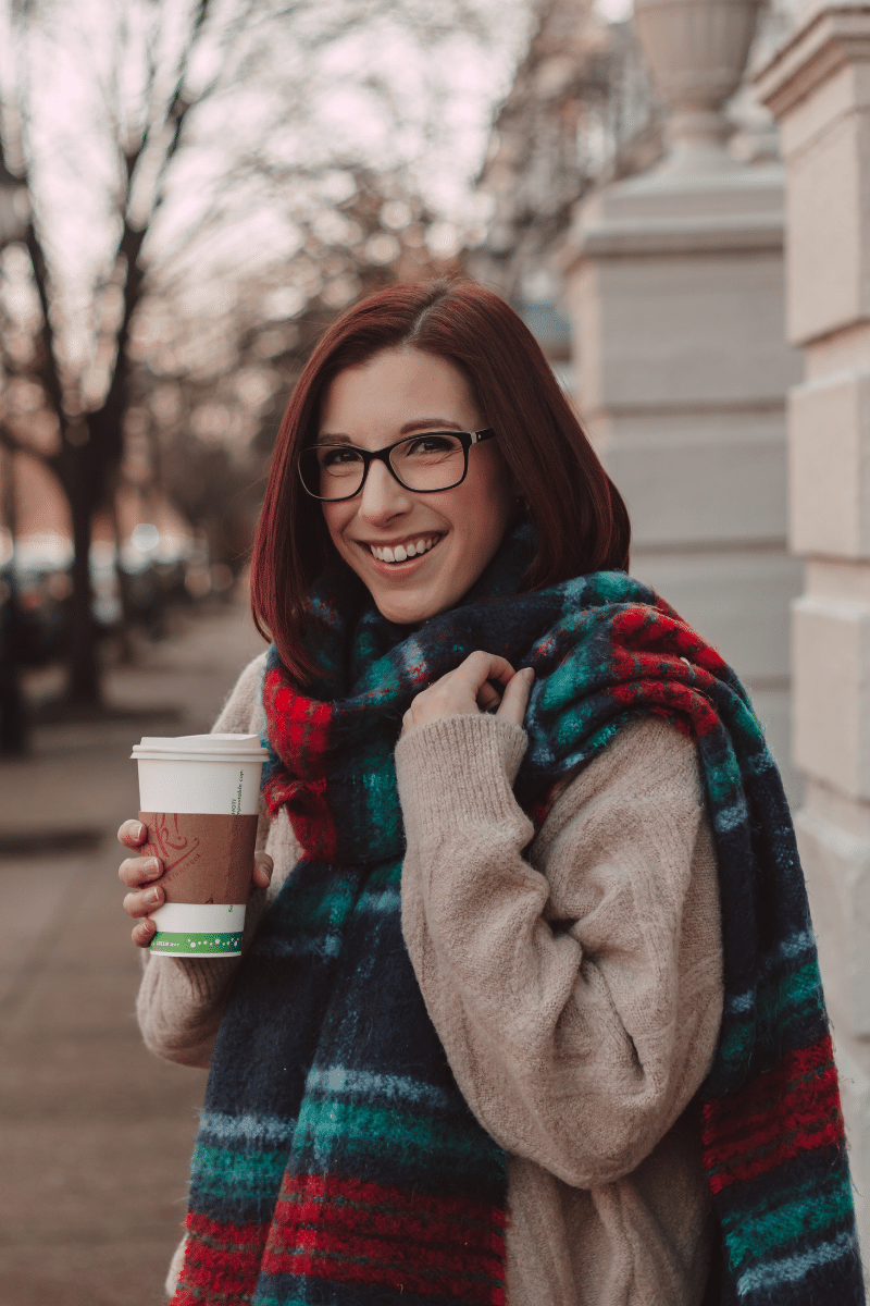 girl wearing plaid wool scarf and holding coffee