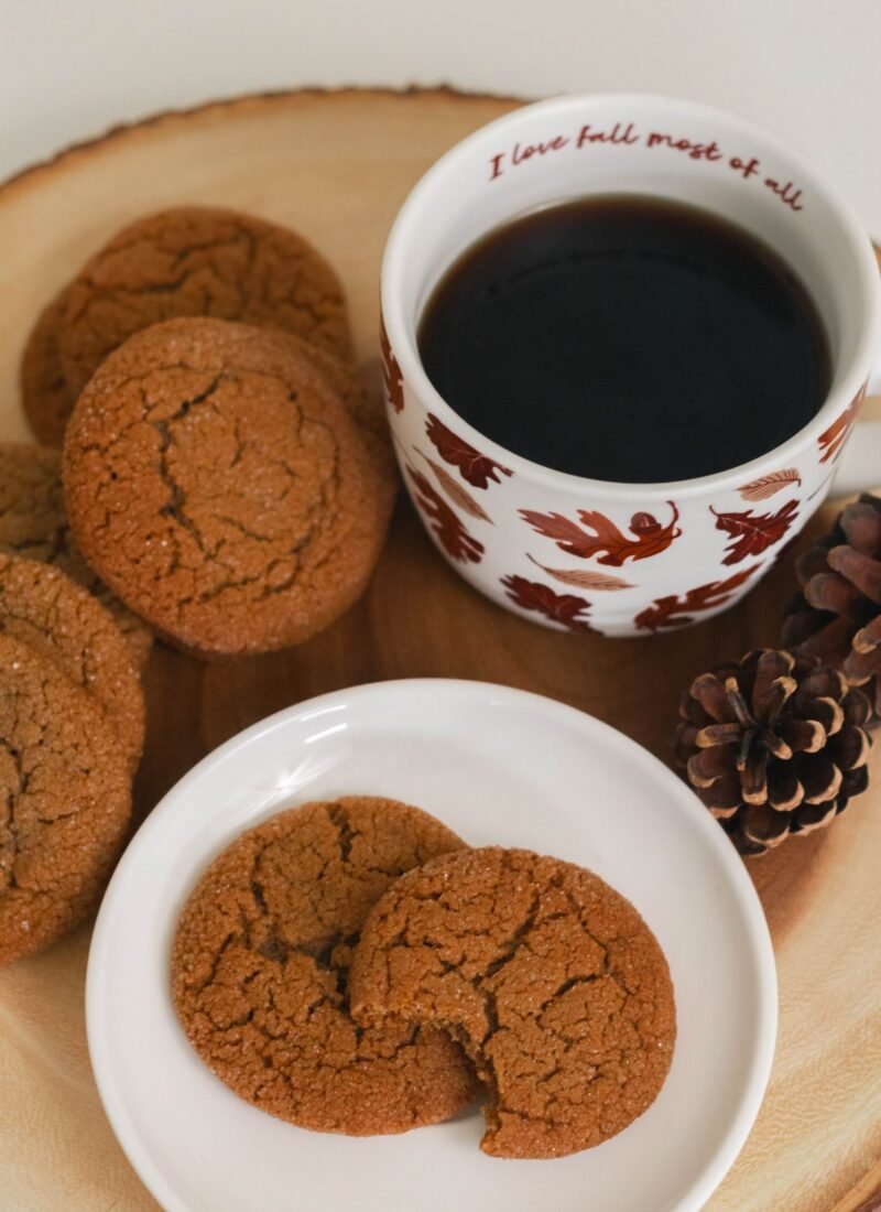 two cookies - one with a bite taken out of it - on a play next to a mug of black coffee