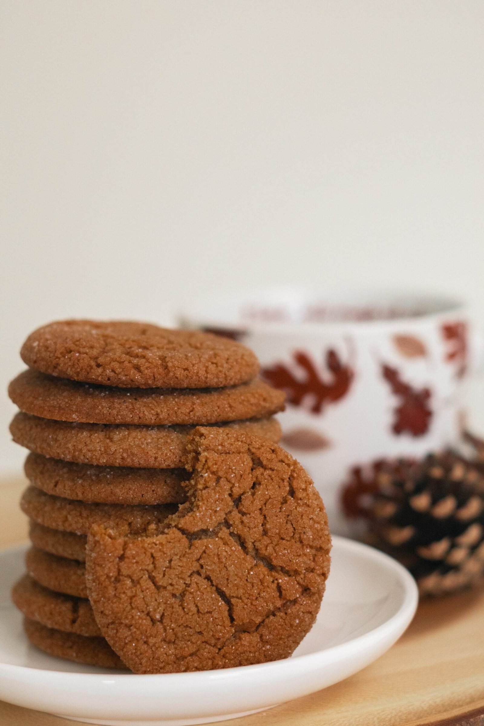 a cookie with a bite taken out propped against a stack of cookies with a mug in the background