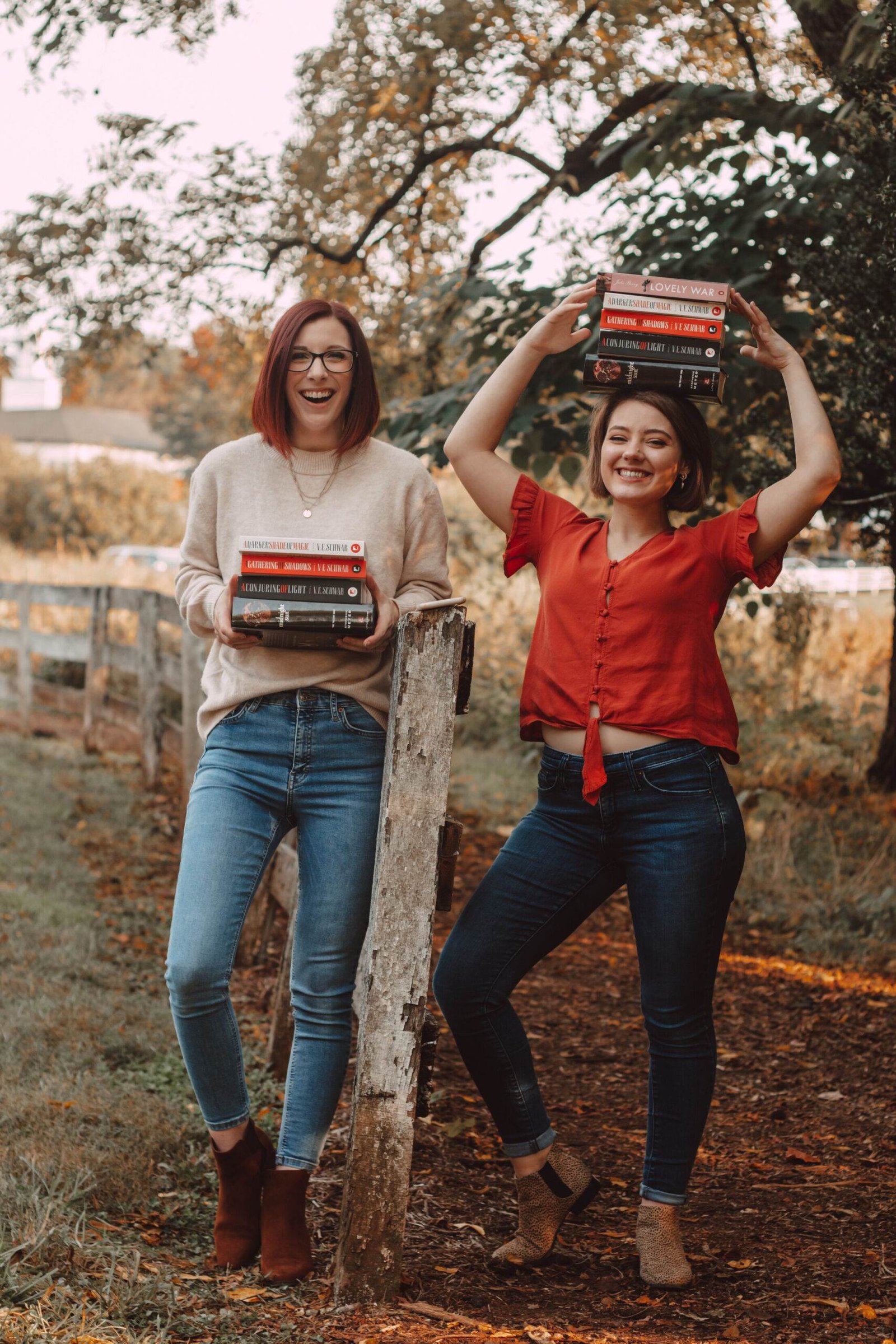 two girls holding the shades of magic trilogy by a fence