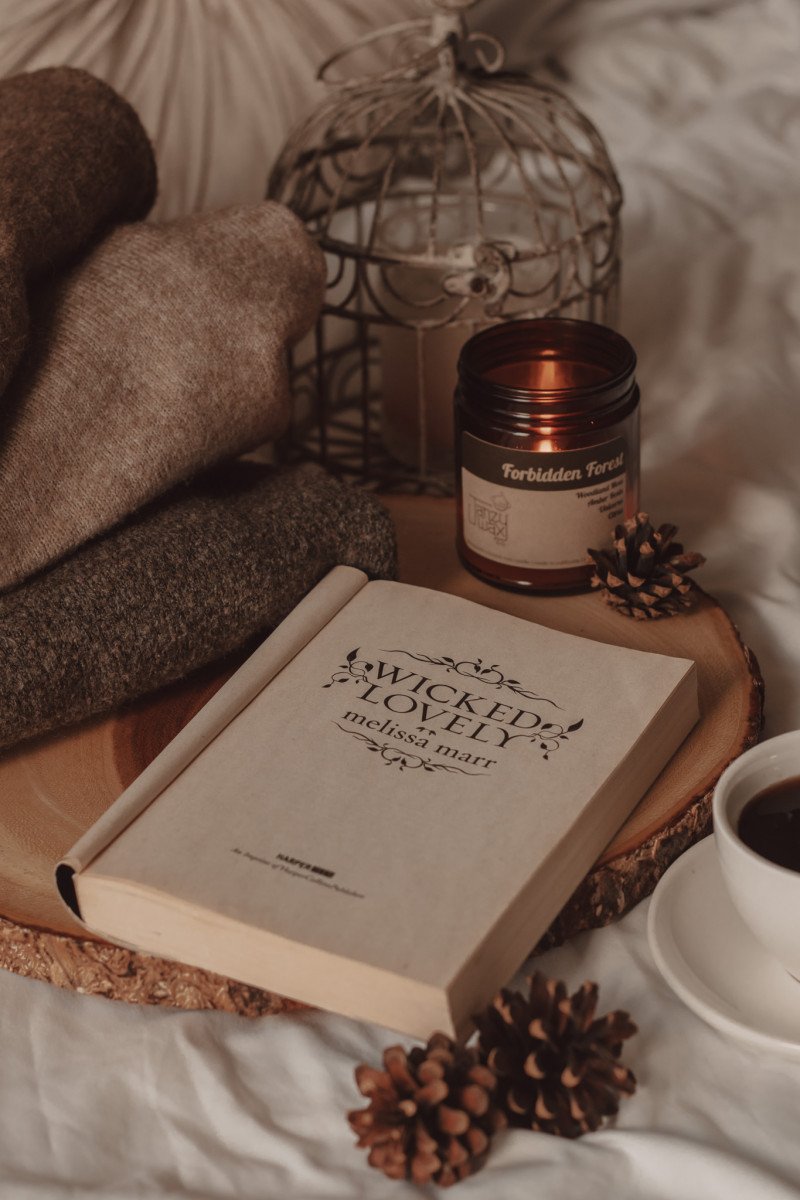 Wicked Lovely by Melissa Marr open to reveal the title page by a burning candle and a mug of black coffee